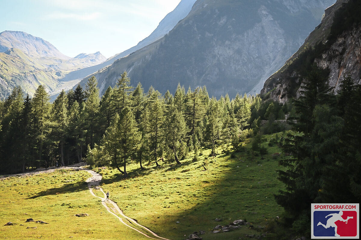 Runner on a single track through an alpine valley